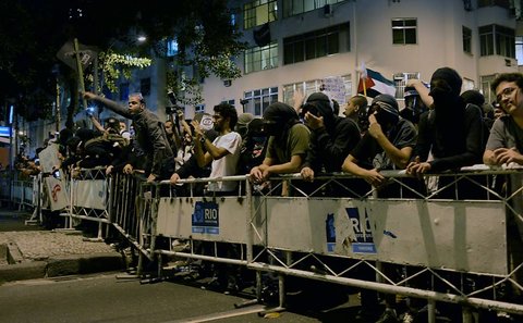 An image of Monday's protest in Rio before clashes broke out, showing a protester who was arrested later standing on a barricade with his fist raised.
